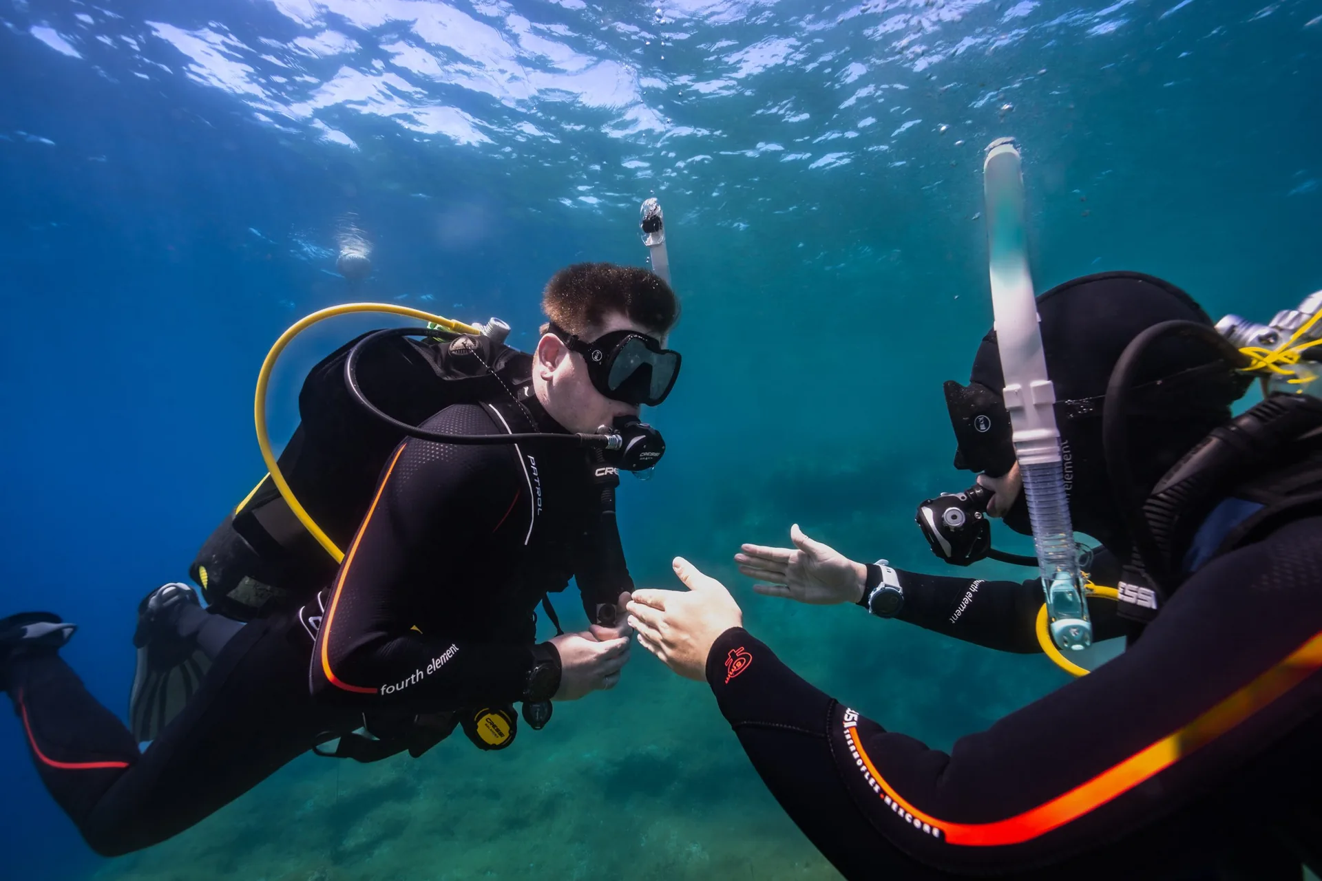 Dos buceadores se comunican por señas bajo el agua durante el curso Divemaster