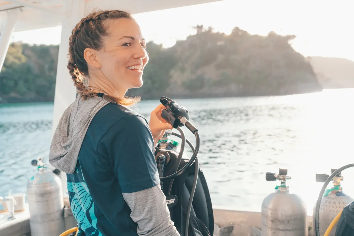 Instructora sonriente en el barco, junto a las botellas, mirando al mar