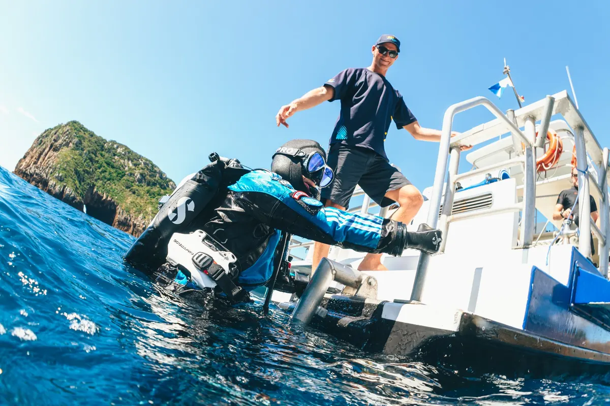 Un instructor en la plataforma del barco mientras un buceador entra al agua