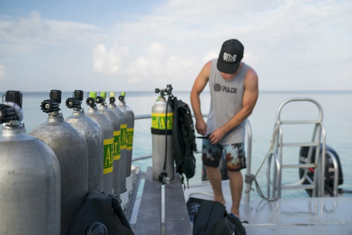 Un instructor con gorra prepara botellas alineadas en la plataforma de un barco