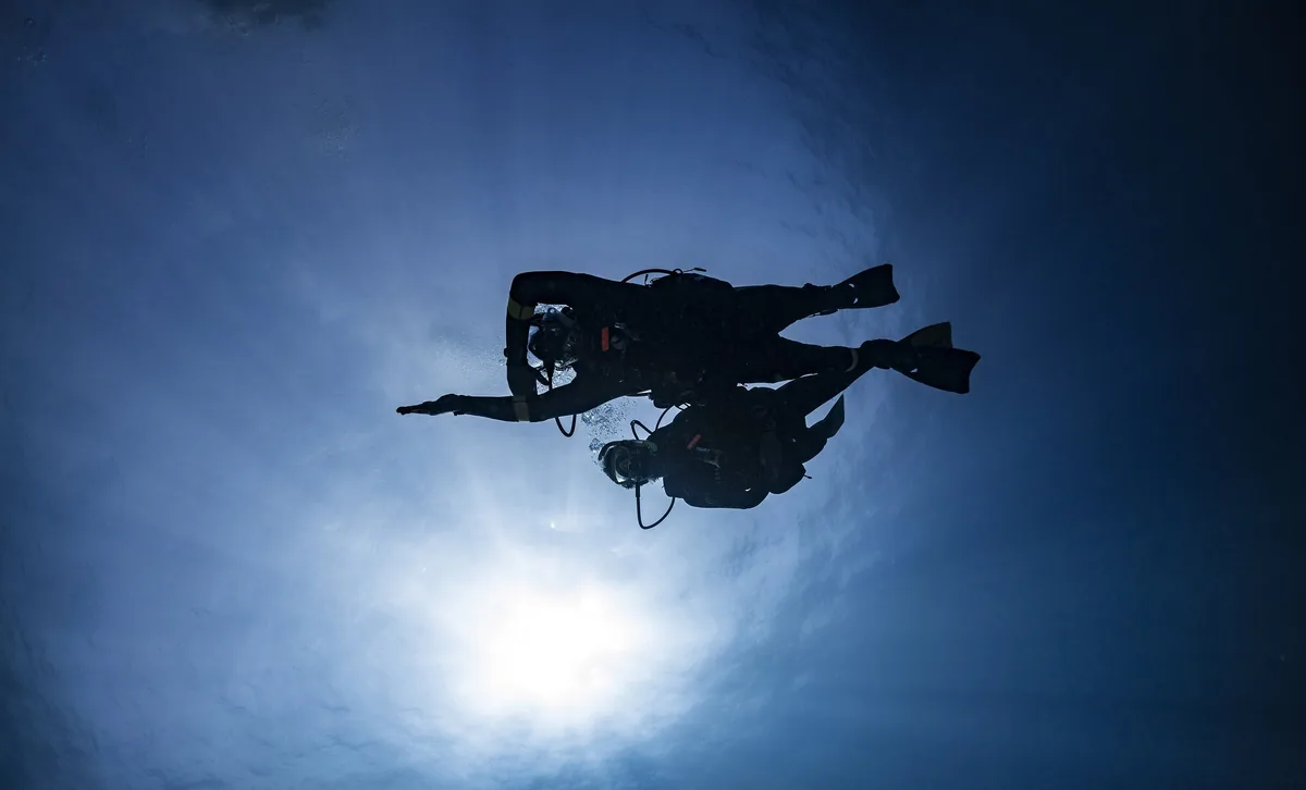 Silueta de un buceador a contraluz del sol en un azul profundo