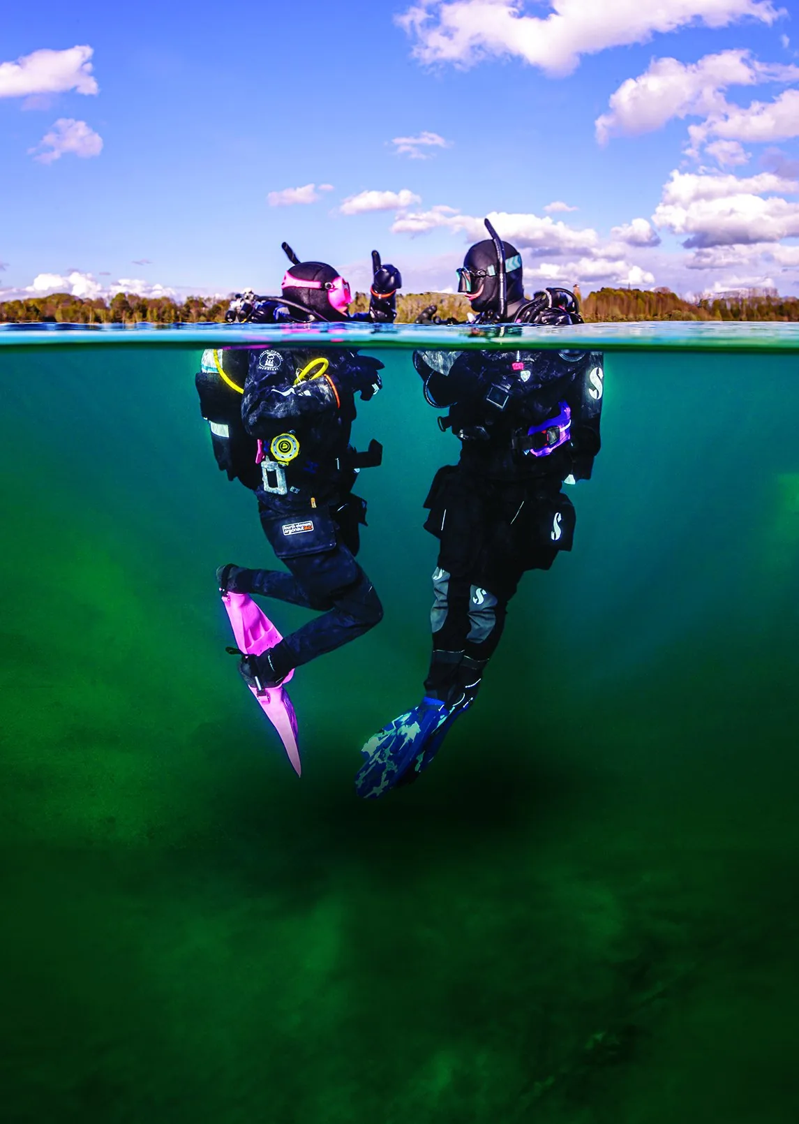 Dos buceadores en una foto partida sobre y bajo el agua con cielo nublado