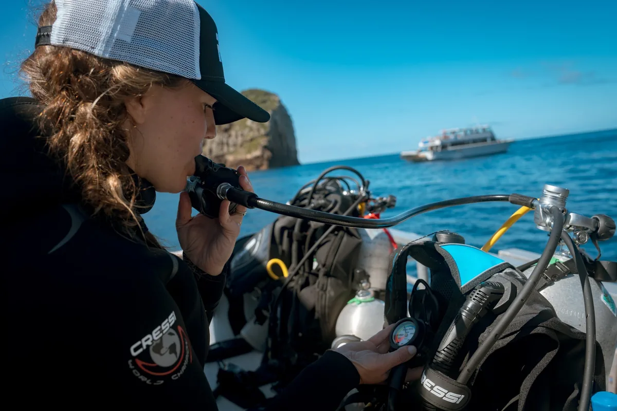 Instructora con gorra comprueba el regulador de un equipo en la cubierta del barco