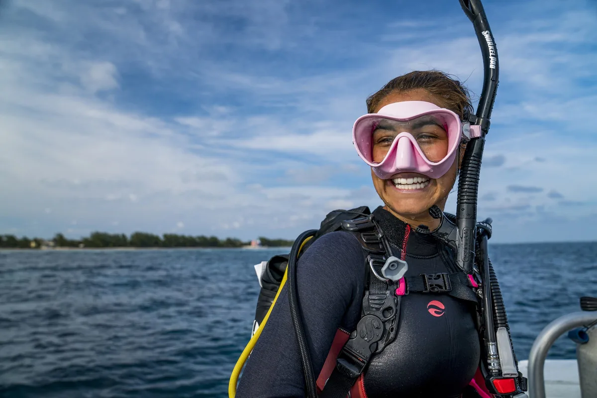 Buceadora sonriente con máscara rosa y snorkel en la superficie del mar