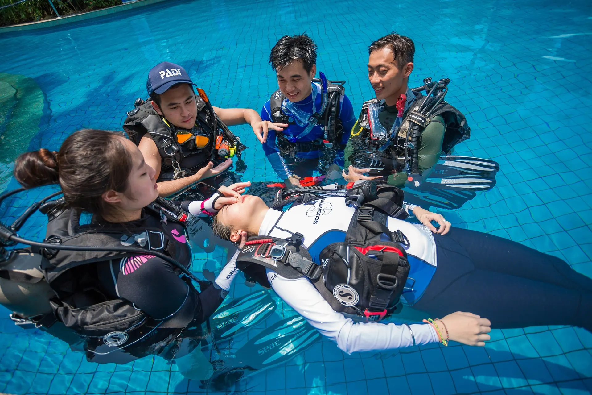 Clase de rescate en piscina vista desde arriba con buceadores rodeando a un compañero